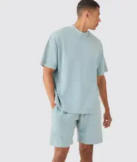 A man wearing matching co-ord set of oversized t shirts and shorts in steel grey colour